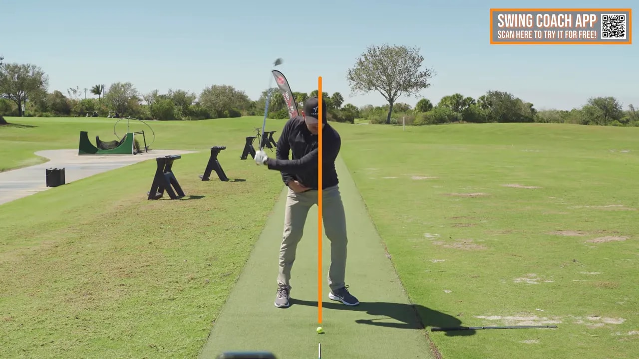 Golfer demonstrating hips-forward downswing start with head staying back over the ball line on a practice range
