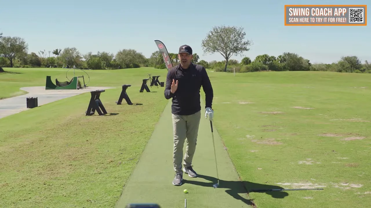Instructor explaining hips-forward downswing concept on a golf practice range