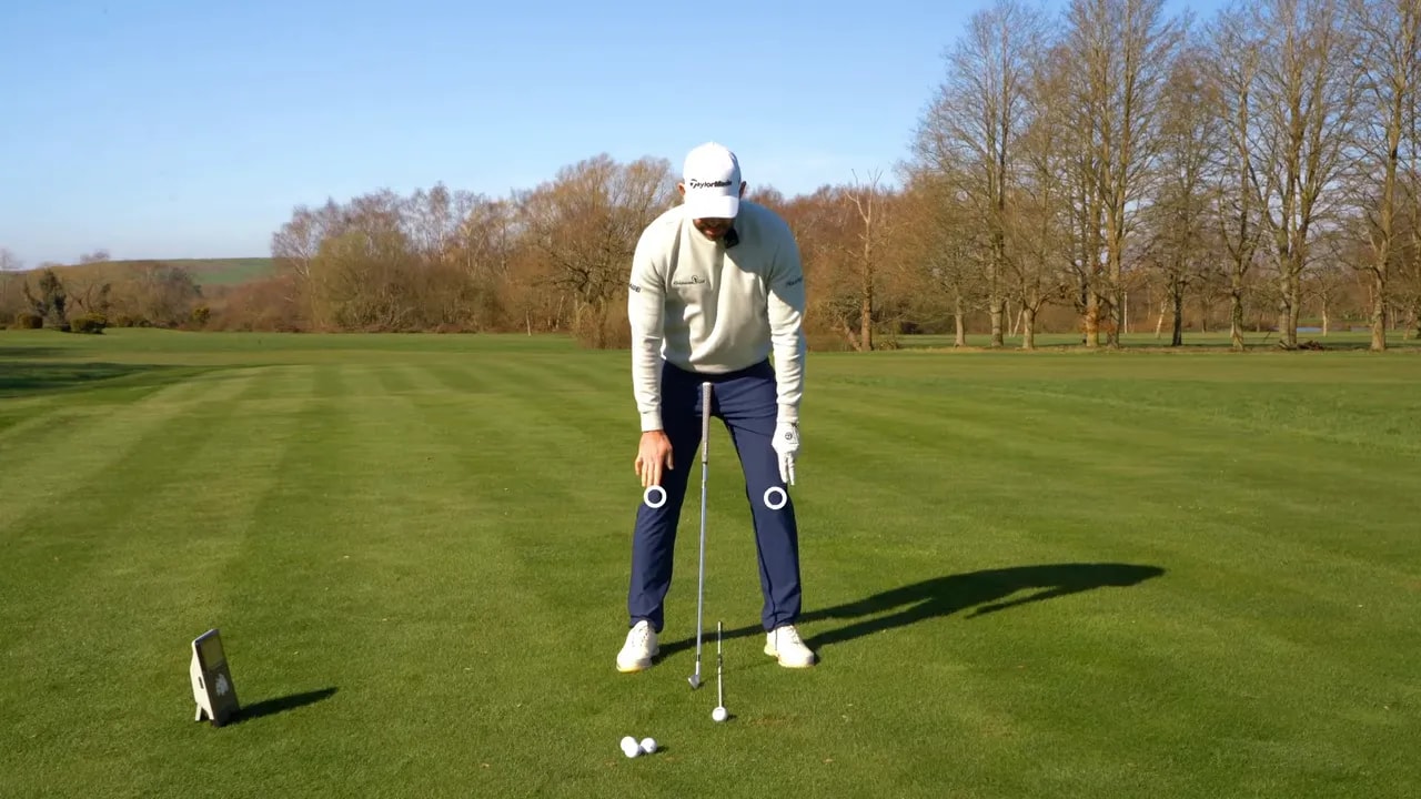 Golfer at address with two pressure reference circles near feet indicating a lead-side pressure bias