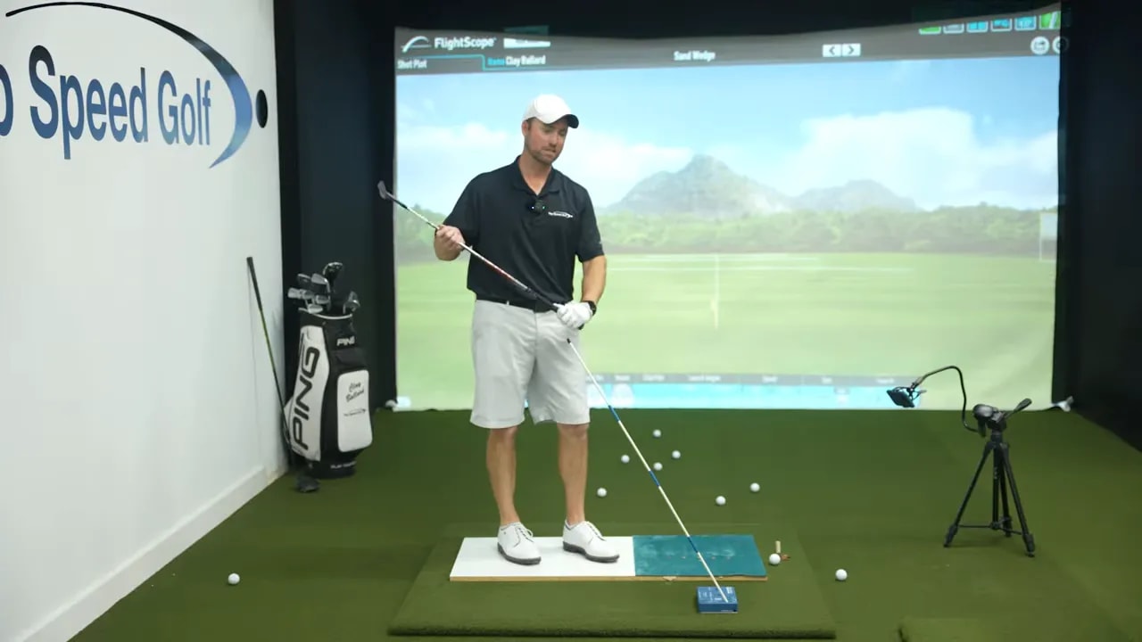 Golfer mid-swing position with brick alignment guide to keep club more on top for chipping pitching