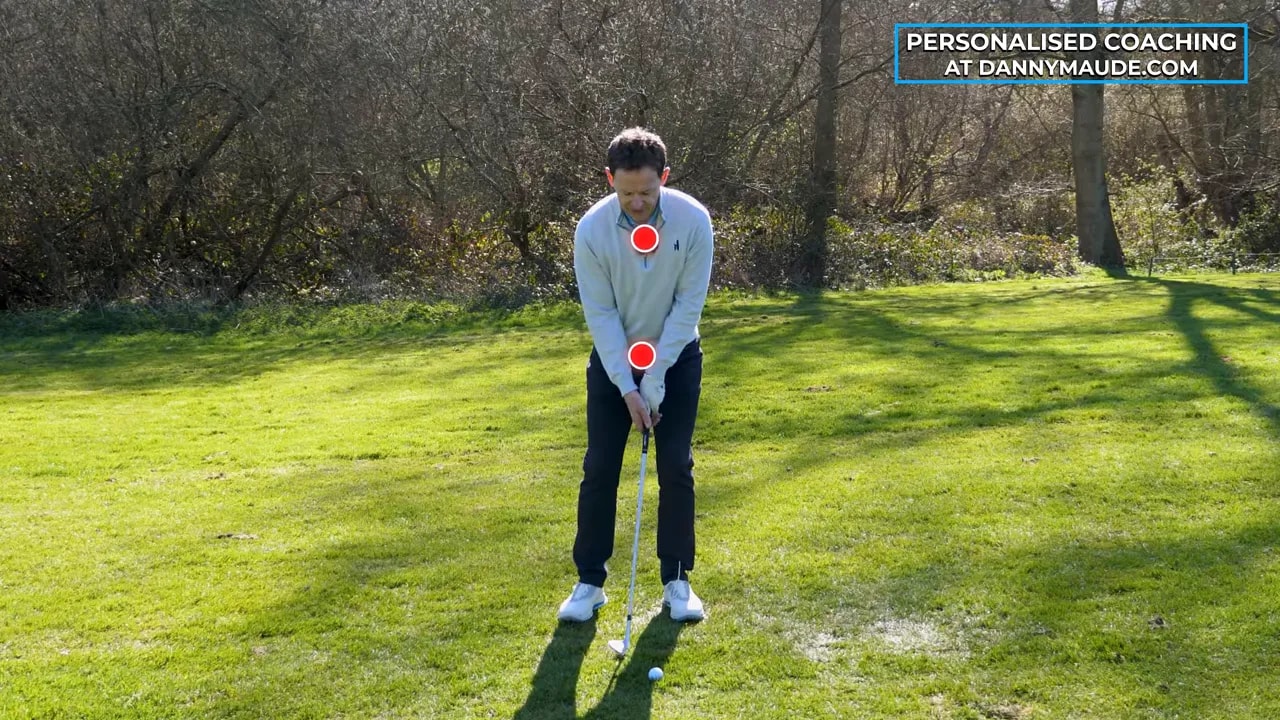 Golfer demonstrating stacked pitch shot setup with red alignment markers for body positioning