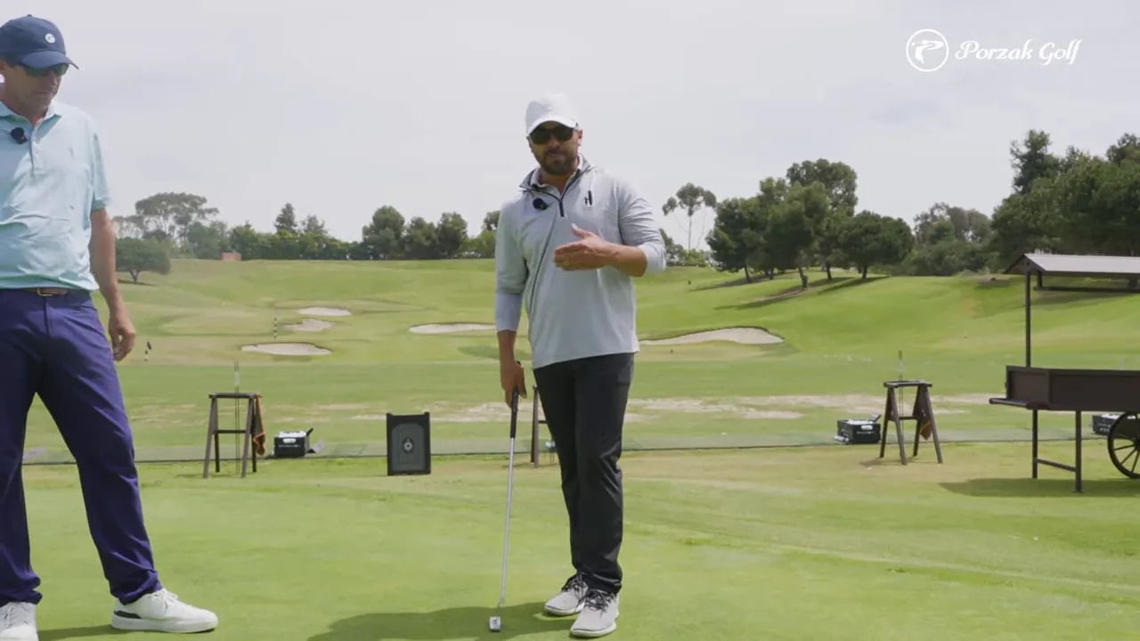 Golf instructor demonstrating a calm putting pre-shot setup with training poles on a practice green