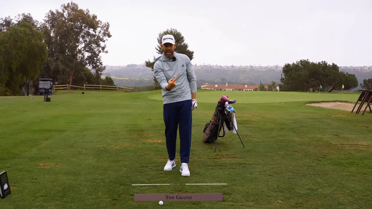 Golf coach-style demonstration of forward pressure for iron compression on a driving range