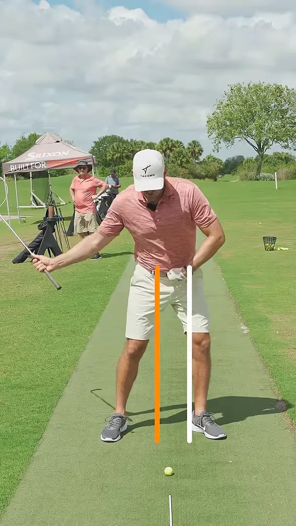 Golfer demonstrating bump and crunch down and forward with alignment lines on practice range