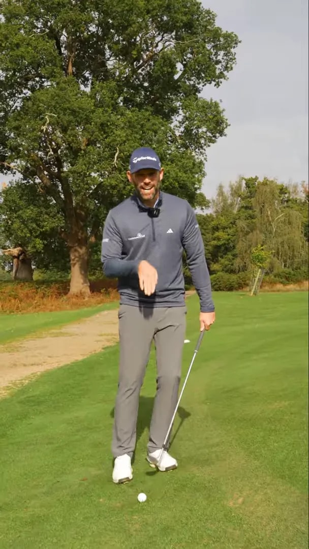 Golfer demonstrating a controlled chipping setup on an upslope green with a wedge