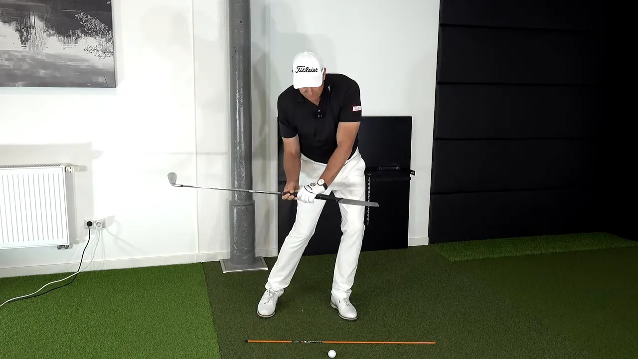 Golfer demonstrating the deep handle feel with a taped knife-like club prop drill