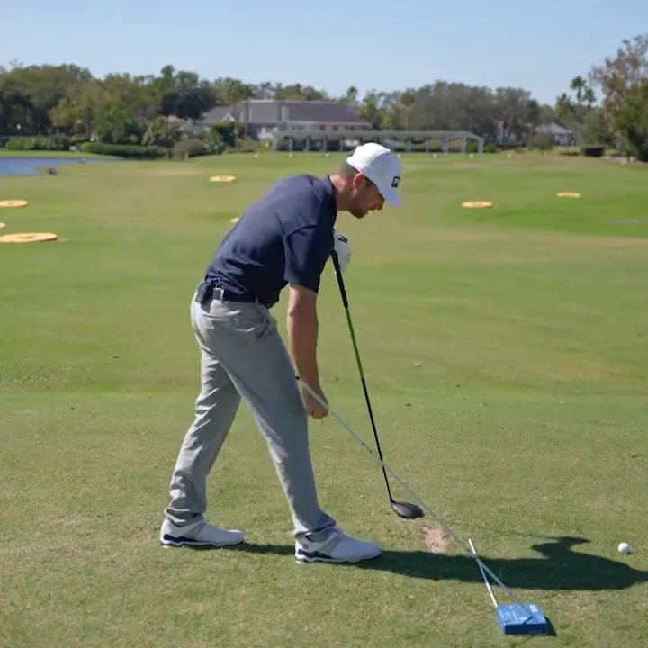 Golfer preparing a driver obstacle drill with a training aid barrier