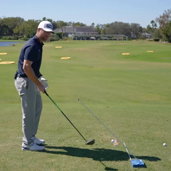 Golfer practicing driver swing alongside a barrier obstacle and tee shot markers