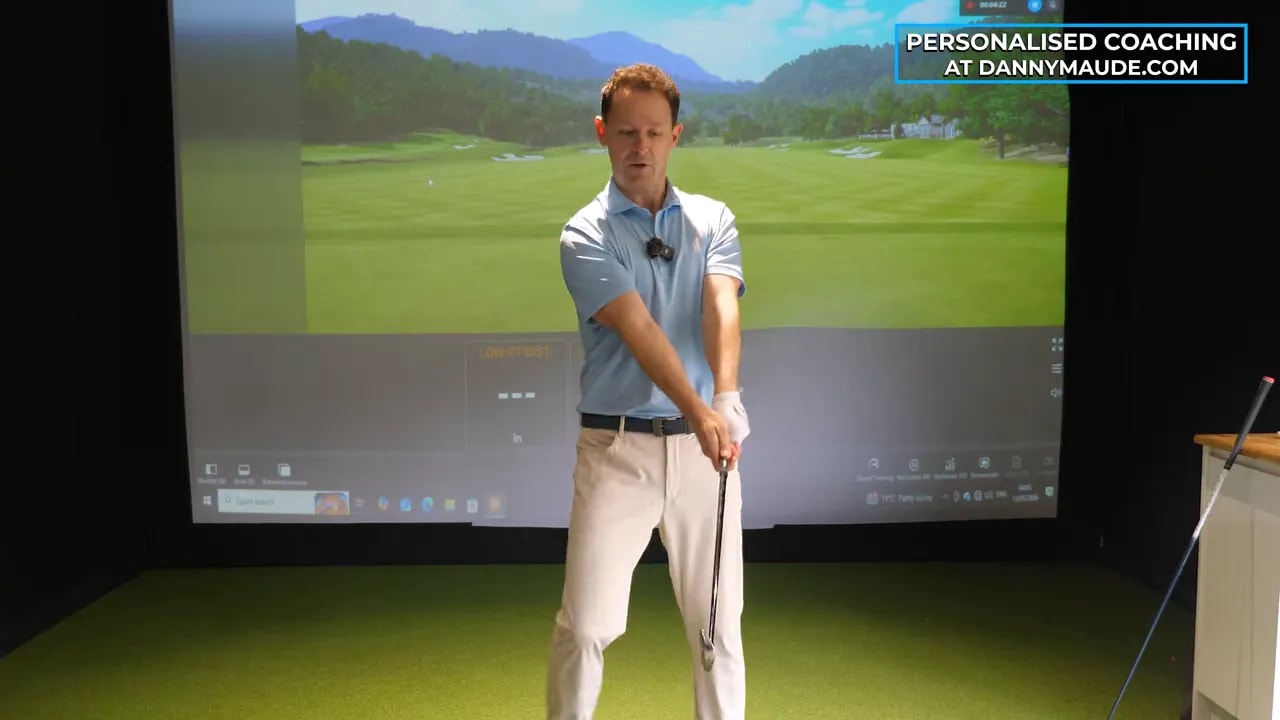 Golf coach demonstrating educated hands downswing lever-and-pressure feel in an indoor golf bay