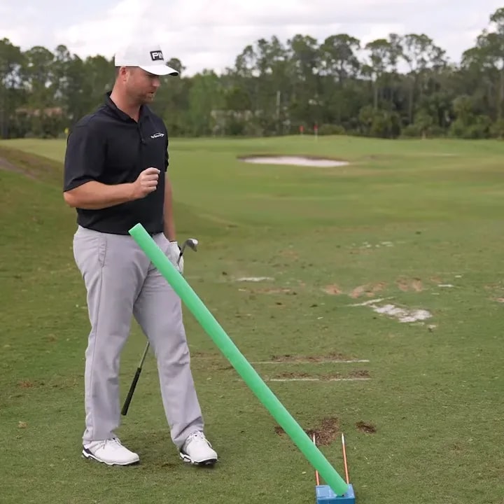 Golfer demonstrating a fade practice setup with alignment aid on a golf range