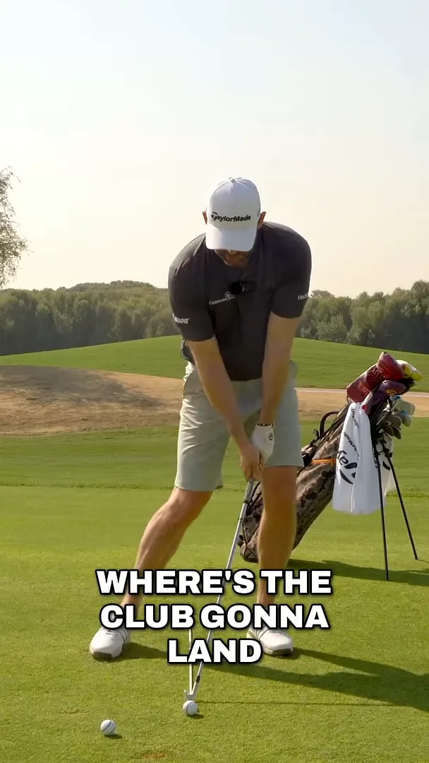 Golfer pointing to the area where the club should land after starting down to improve low point