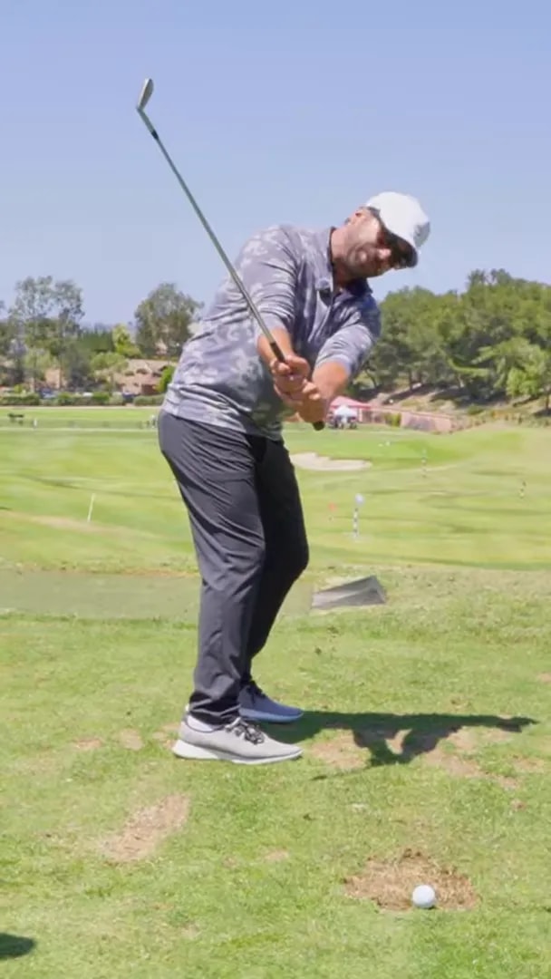 Golfer demonstrating a connected early backswing position with club on the path