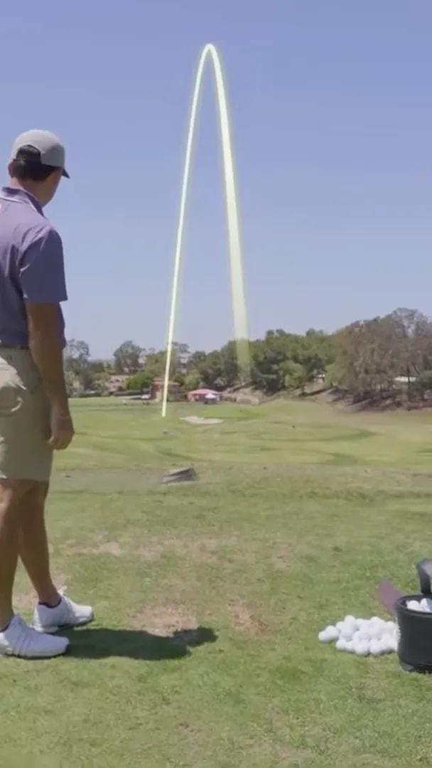 Golfer demonstrating a low, penetrating ball flight with a swing training aid on the range