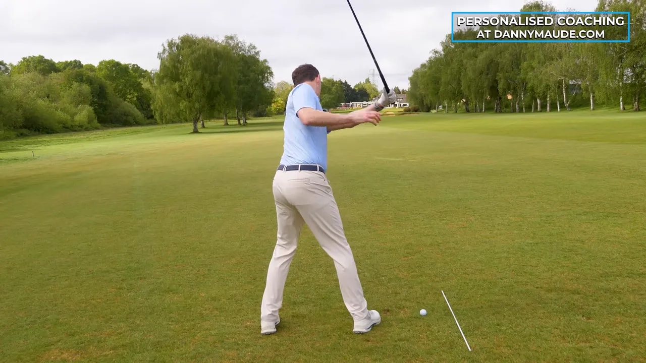 Golfer practicing a fairway wood swing while keeping head centered for more reliable contact
