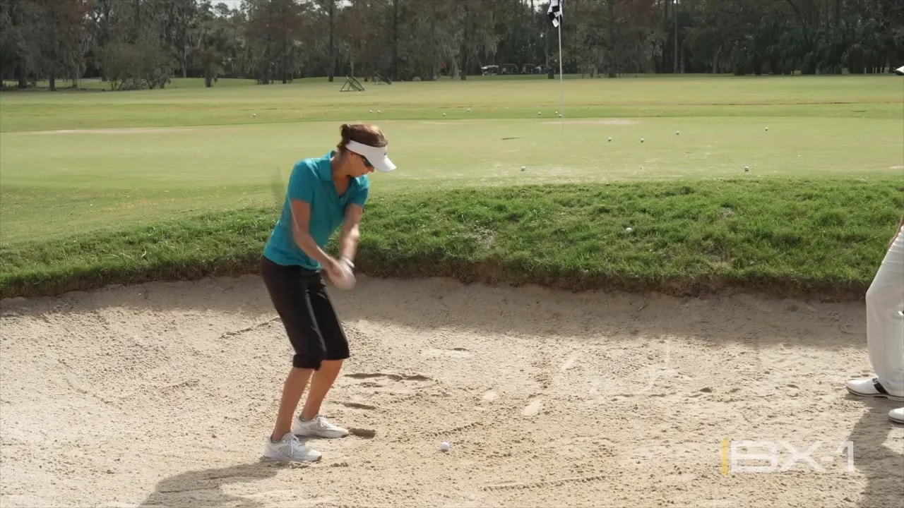 Golfer setup in a sand bunker showing square stance and ball positioned for a simple shot