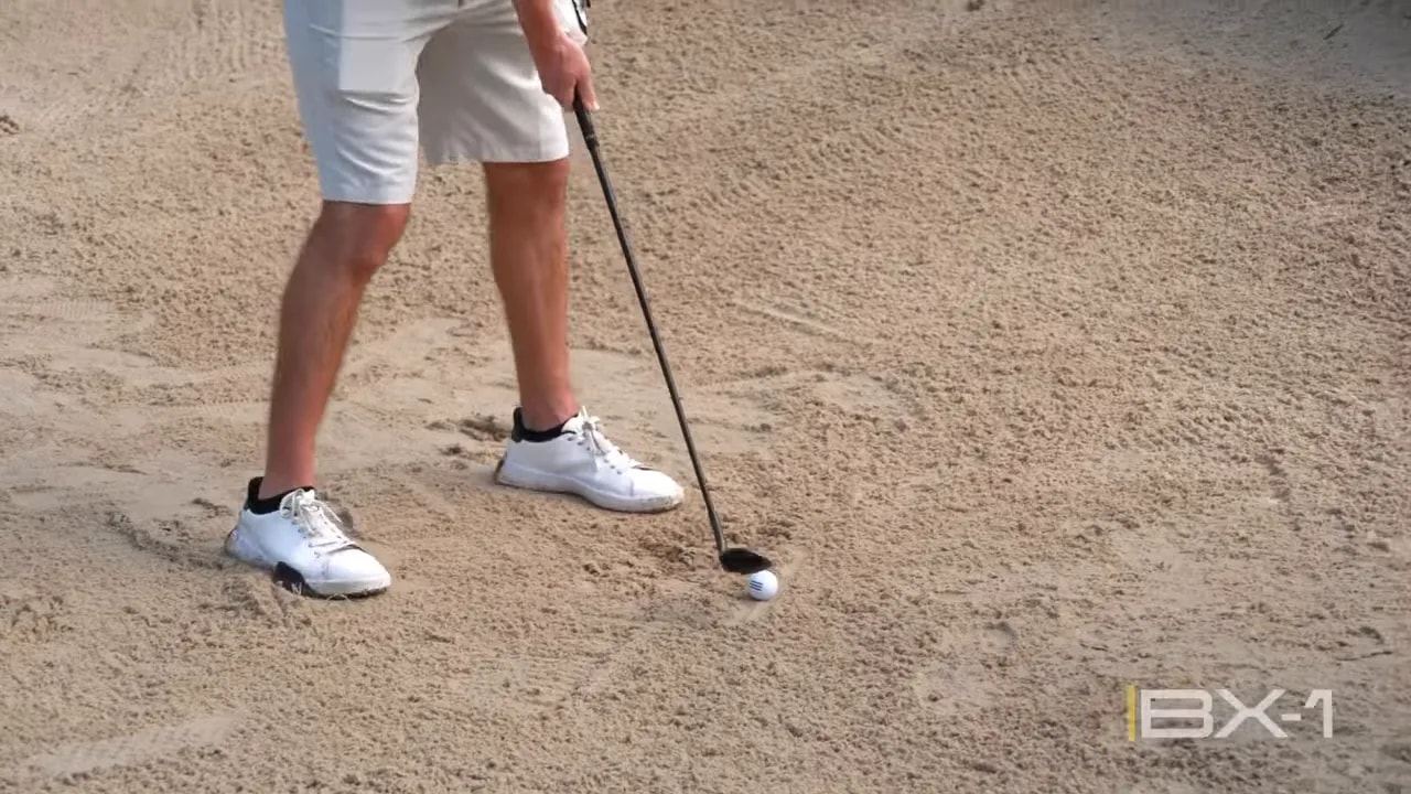 Golfer demonstrates a simple greenside bunker setup with a square stance and ball positioned in the middle of the stance