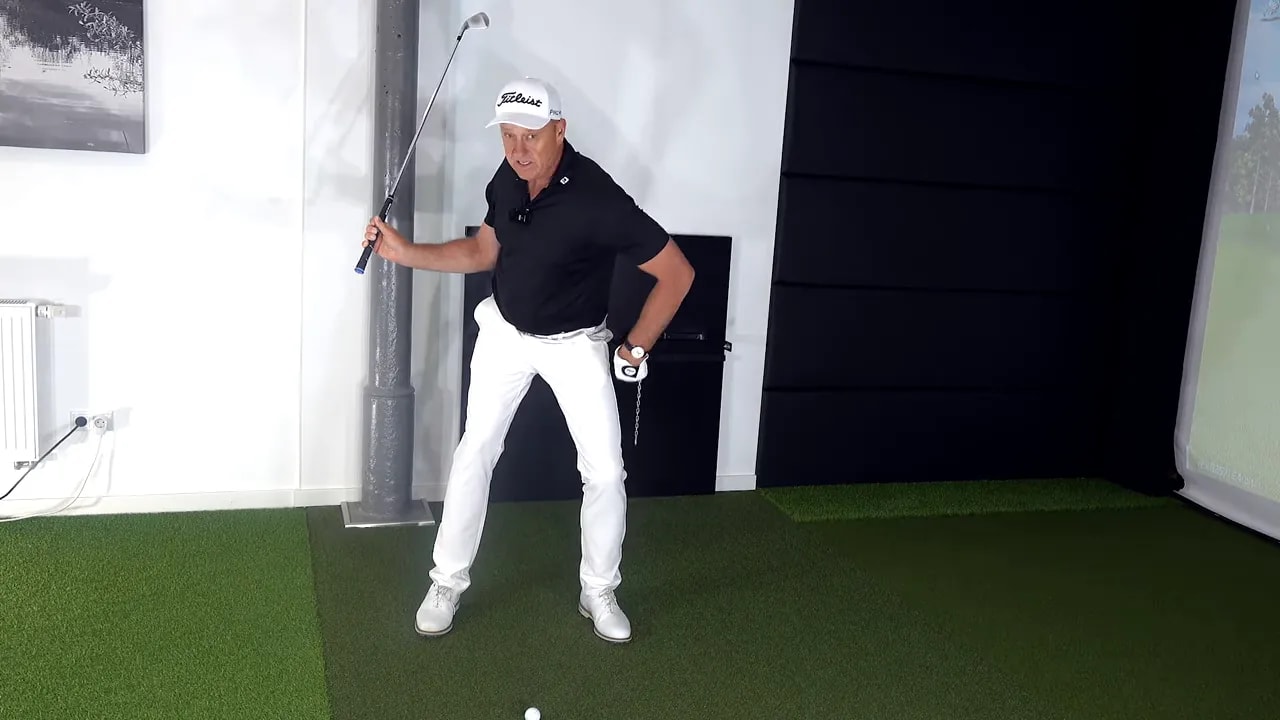 Golf instructor holding a static rehearsal position for a right-side-lowering and connected trail arm drill