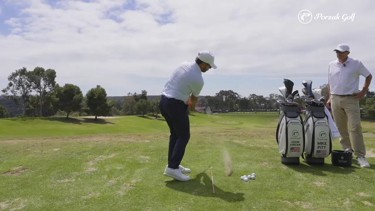 Wedge impact on a practice range showing turf interaction just in front of the ball for compression