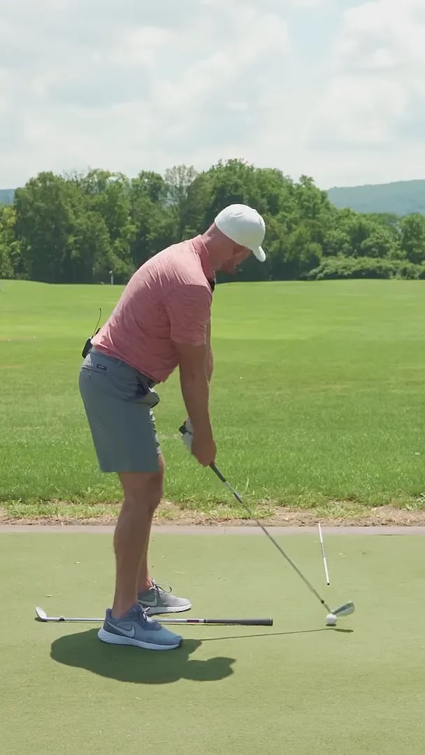 side view of golfer at address with club and training sticks on the ground