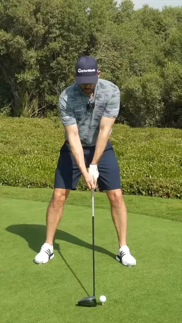 Golfer at address with a red vertical line beside the body during a swing demonstration