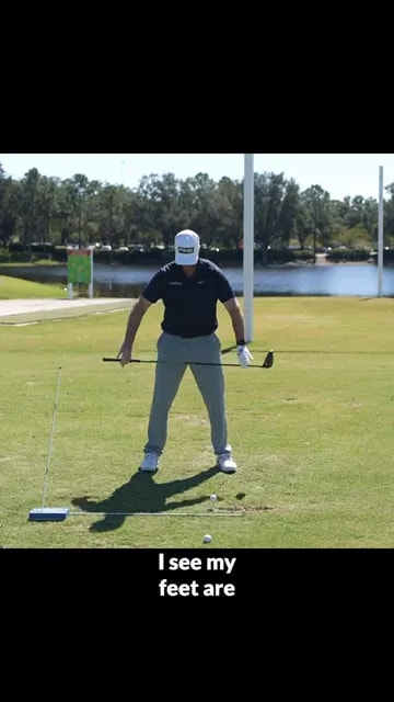 golfer at address with driver and alignment stick on the ground showing stance direction