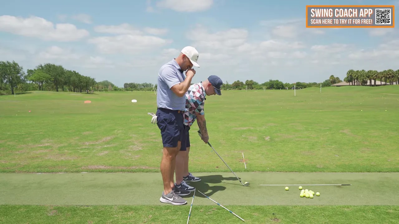 Coach and golfer on range with alignment sticks laid on the ground to show swing path stations