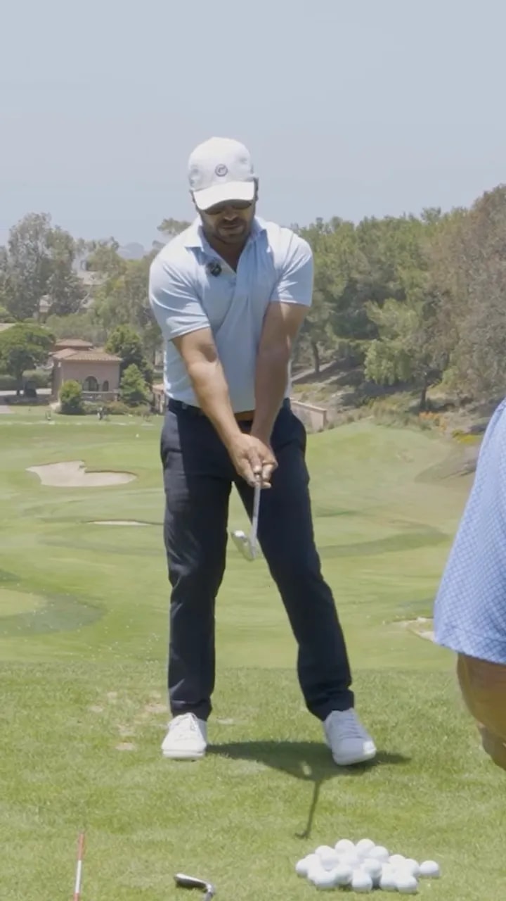 golfer demonstrating the start of the takeaway with both hands on the club and body centered over the ball