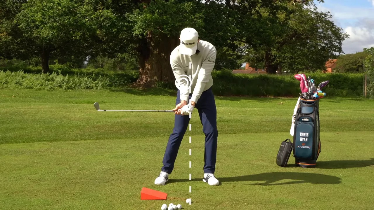 golfer paused in delivery position with a dashed vertical line and red foam block behind the ball
