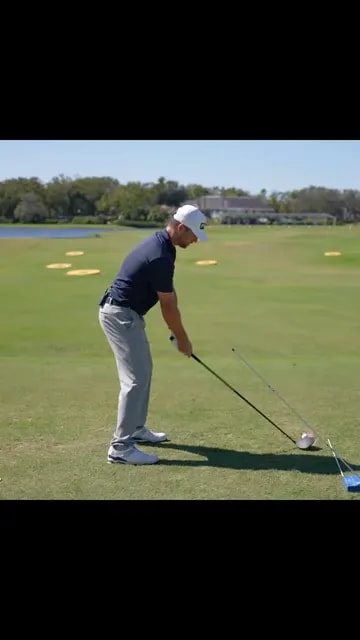 side view of golfer at address with a blue training aid and alignment line on the range