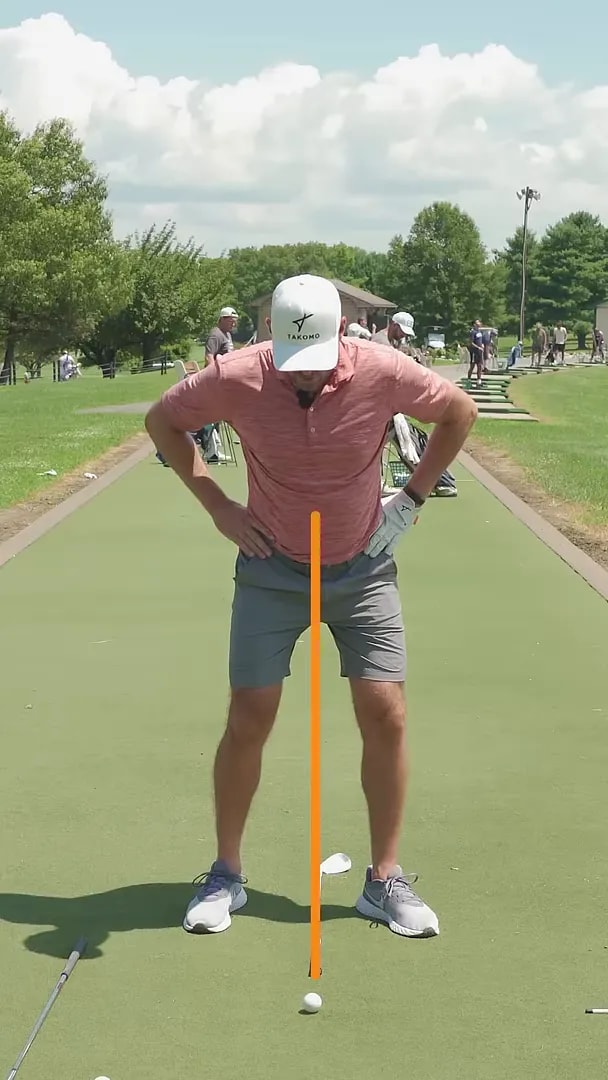 golfer with hands on hips standing over a ball with an orange line between the feet