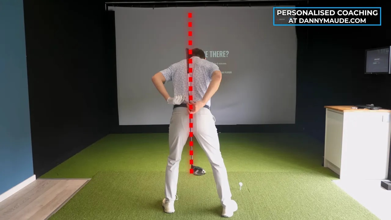 Rear view of golfer with vertical red line overlay while demonstrating body pivot