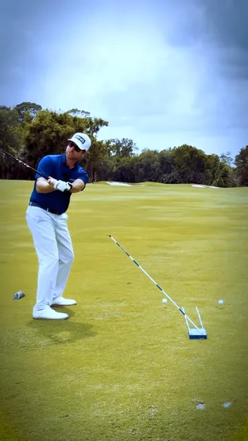 golfer demonstrating a shallowed shaft position in the downswing beside an angled guide