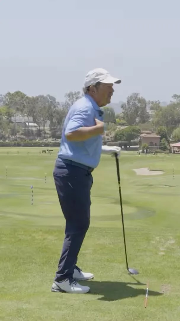 golfer demonstrating a side view shoulder turn on a practice tee