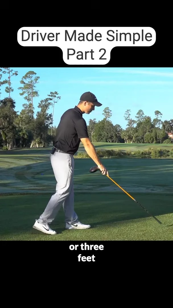 golfer pointing a yellow alignment stick toward the ground in front of the ball area