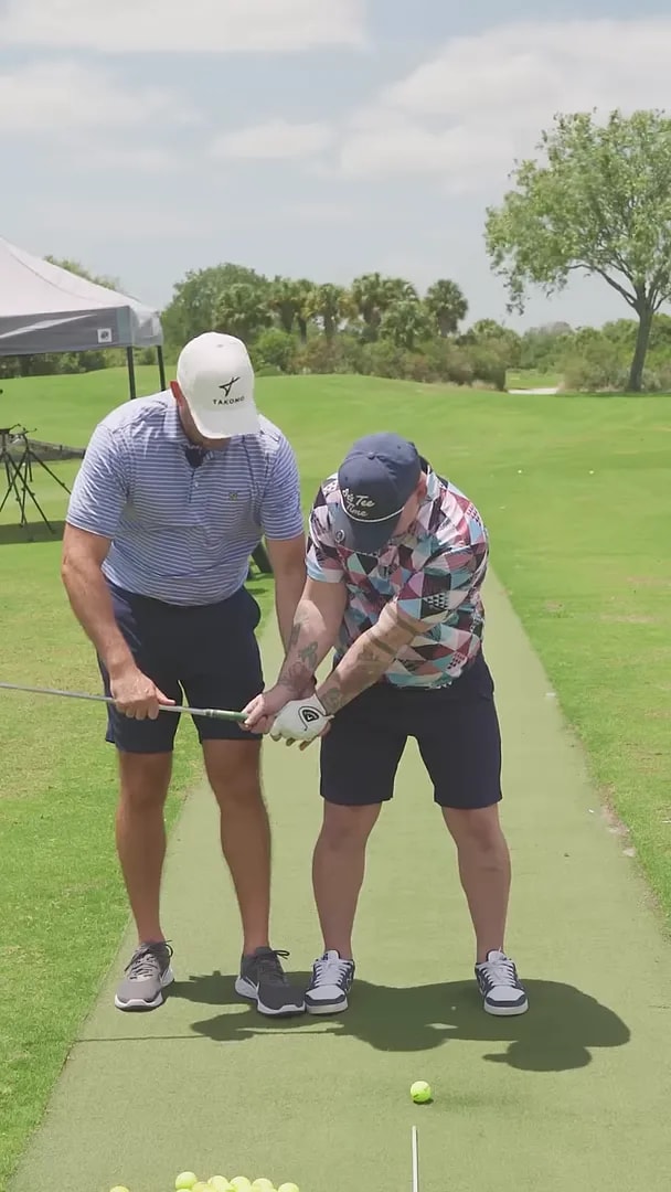 coach and golfer holding club midway back on practice mat from face-on angle