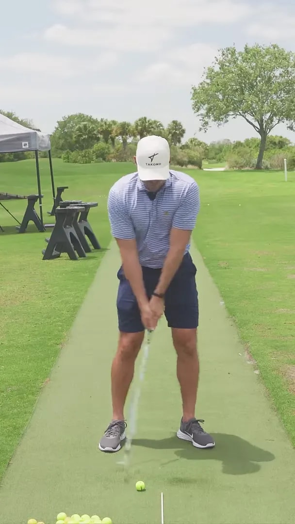 coach at address on mat with ball centered and club in front view