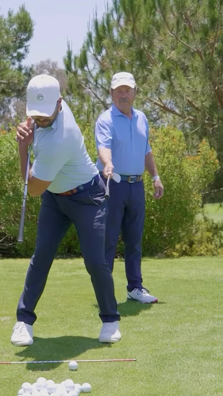 golfer at the top of the backswing with another club held outside the trail hip as a barrier