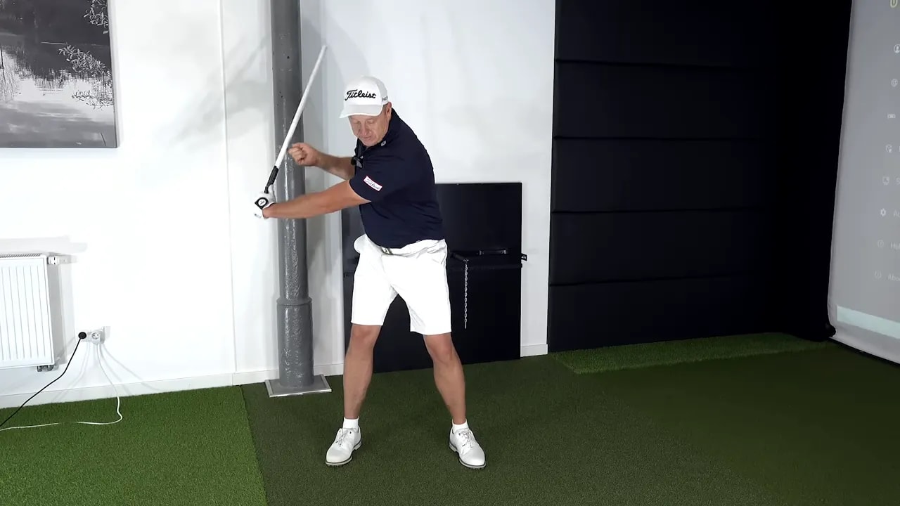 instructor holding alignment stick across body with one finger hooked into the end to demonstrate release checkpoint