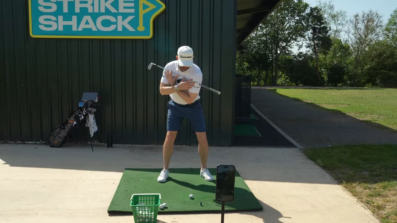 Coach demonstrating backswing pivot with a large green check mark on screen