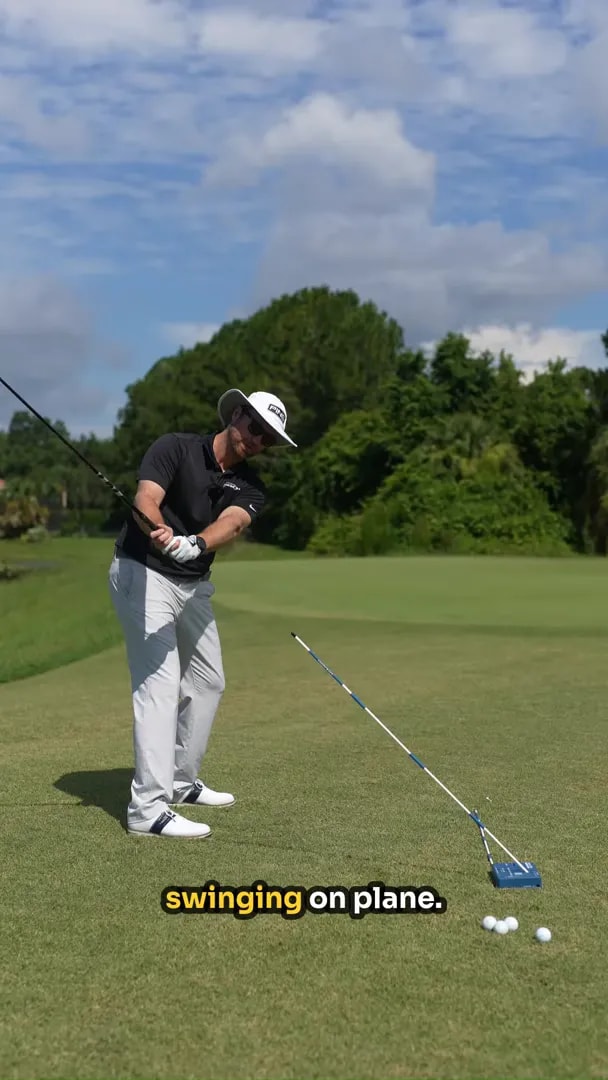 golfer rehearsing a driver swing on plane next to the angled guide