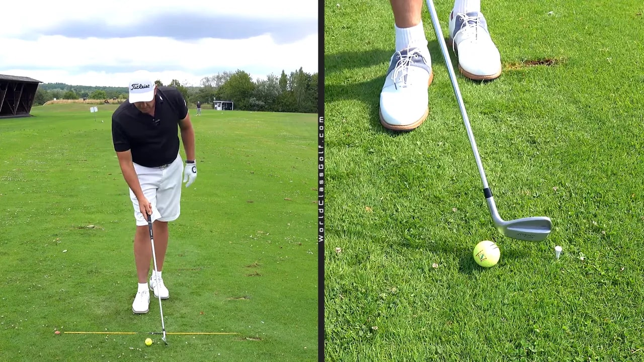 Close view of a golf ball and tee placed ahead of it on grass