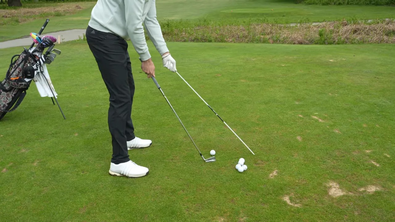 Close view of golfer at address with alignment stick angled near the hands and ball