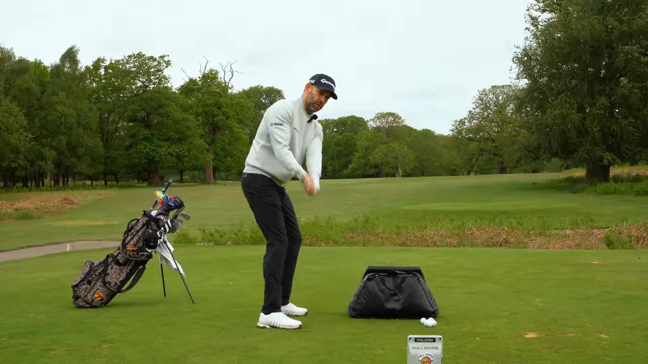 Golfer at the top of a rehearsal near an impact bag
