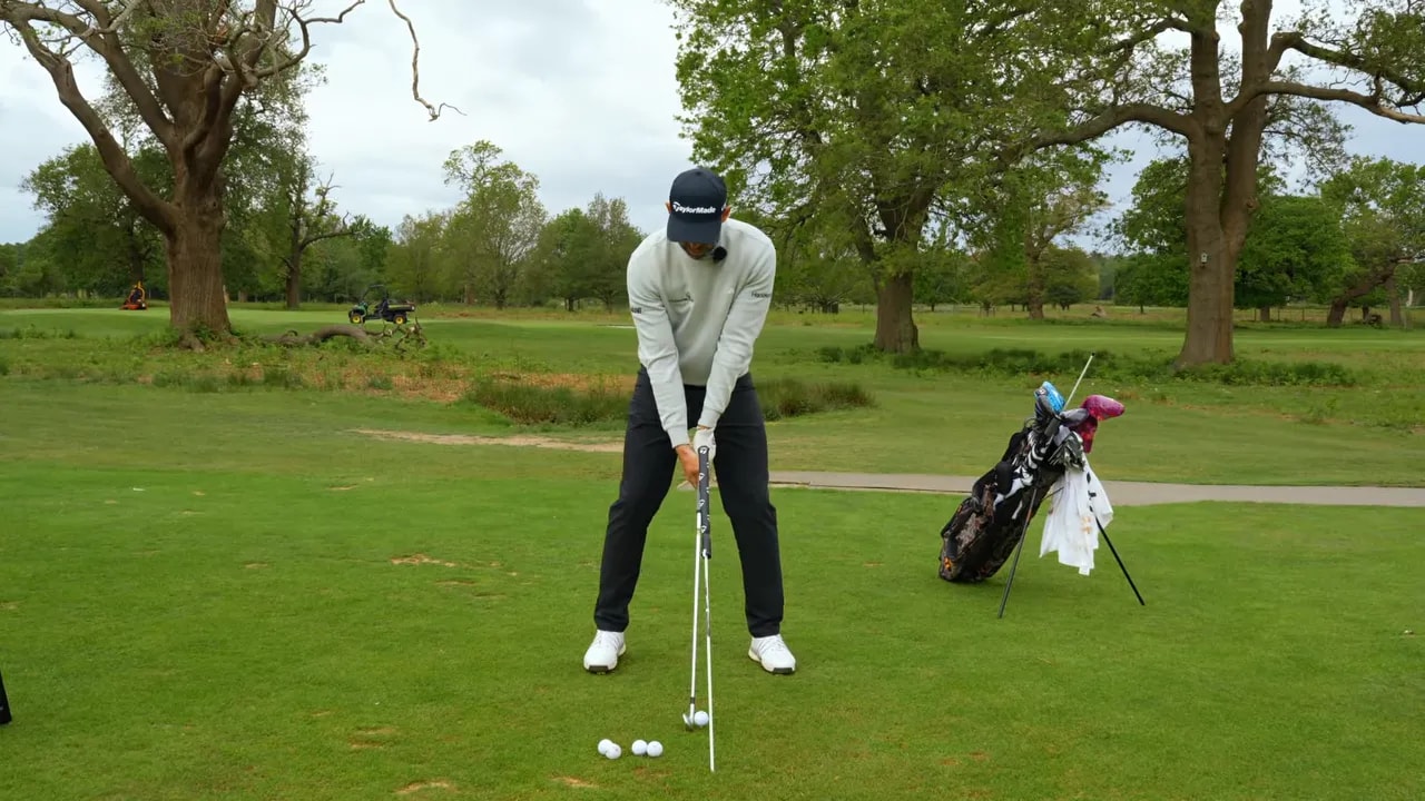 Golfer at address next to an alignment stick set near the ball line