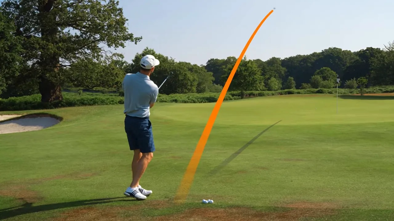 Golf wedge shot with orange high trajectory line toward the green
