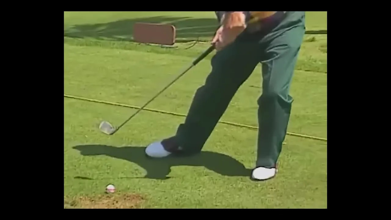 close view of golfer legs and club with lead knee bent forward near the ball