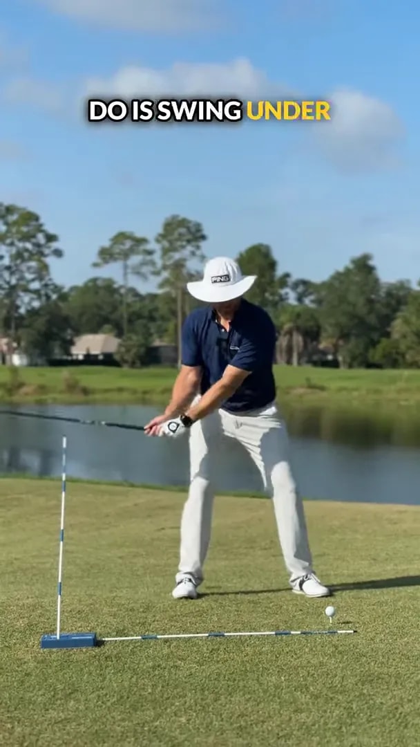golfer at address with alignment stick standing to the left and club set to swing underneath it