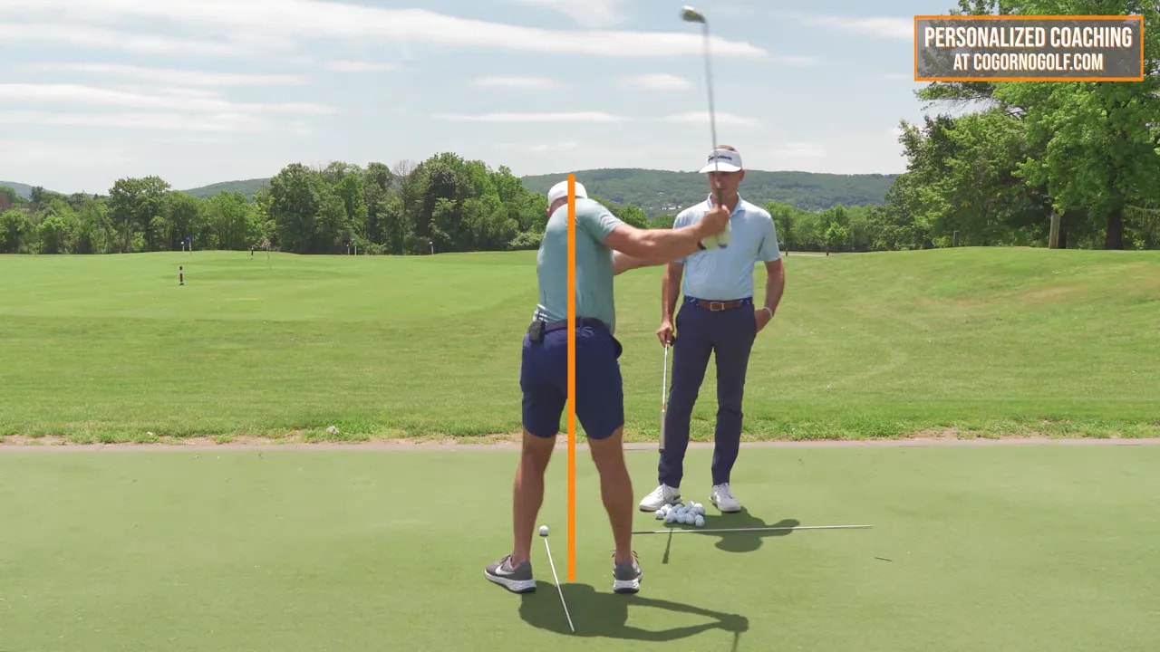 Rear view of golfer at backswing with vertical orange line and text showing trail hip moving around to midline