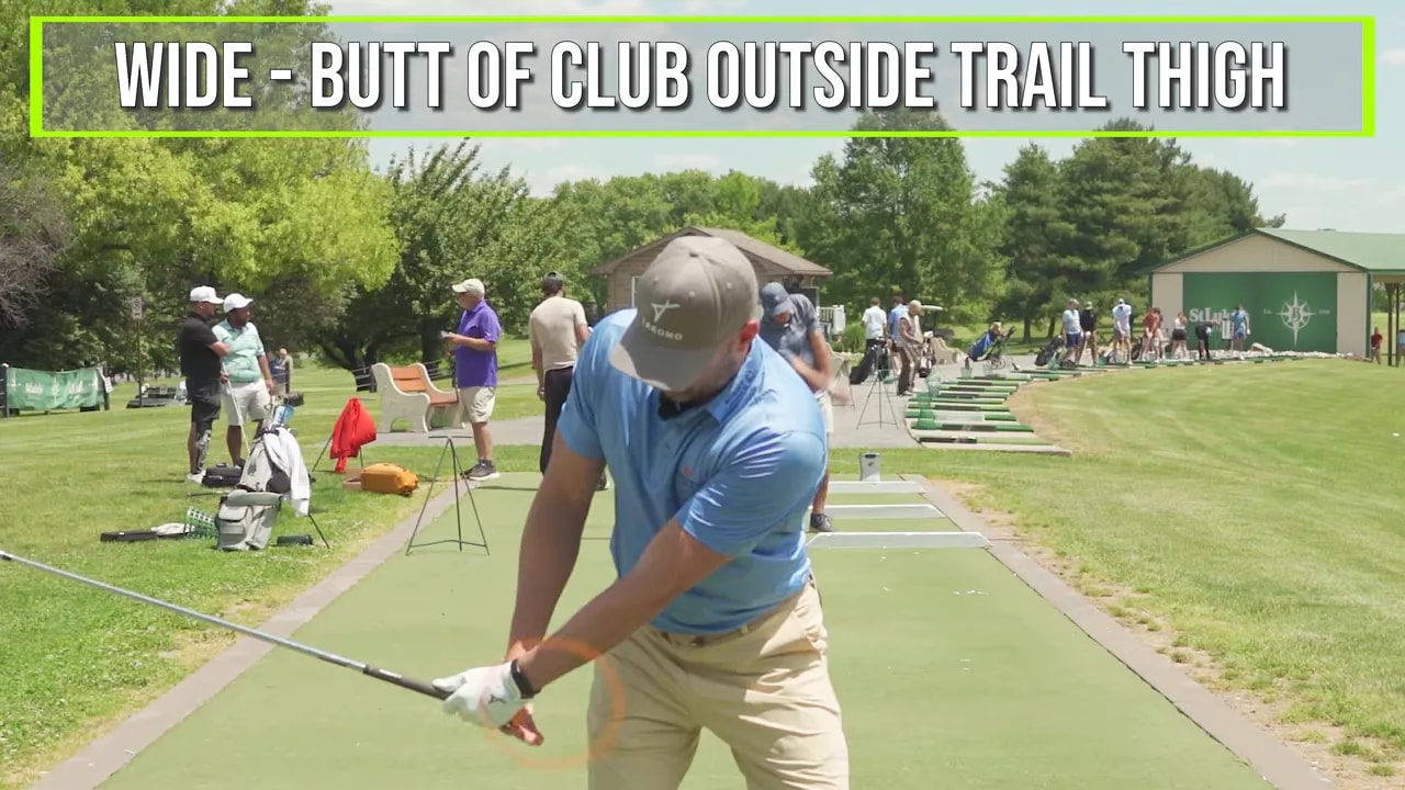 Golfer demonstrating wide takeaway with club butt outside trail thigh marked by an orange circle