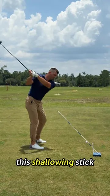 Golfer swinging a driver beside a diagonal alignment stick training obstacle